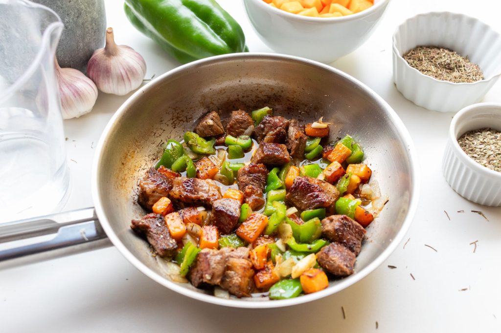 Poêle en inox, vraiment dangereuse — poêle en inox cuisinant des légumes